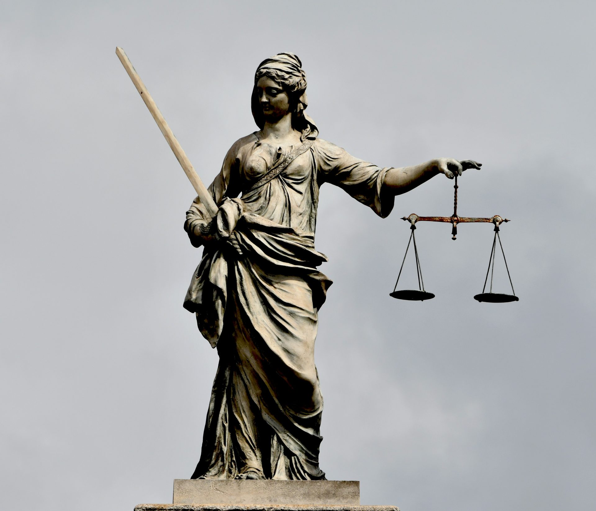 Eine Statue der Justitia, die ein Schwert und eine Waage hält.