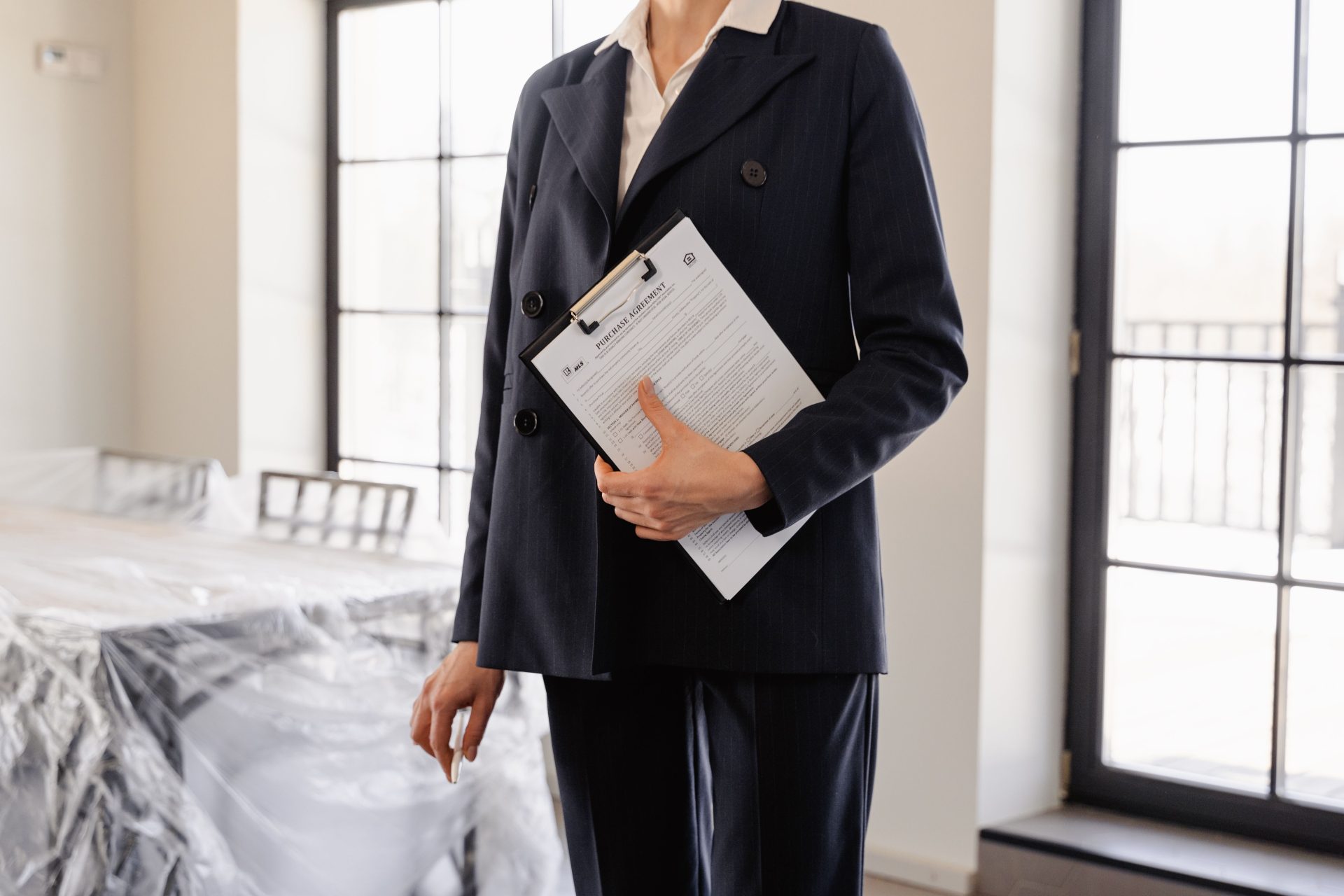 Ein professioneller Immobilienmakler hält in einem sonnendurchfluteten Raum Dokumente in der Hand, die Erfolg und Transaktionen symbolisieren.